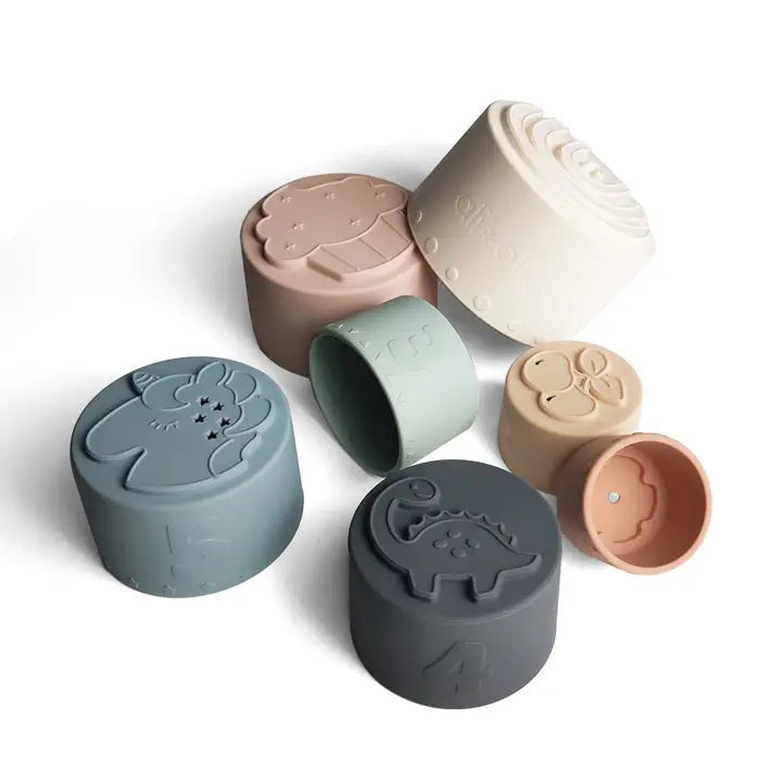 Introducing the LARGE SILICONE STACKING CUPS by ALI + OLI, a delightful collection of neutral and pastel-colored cups designed to promote fine motor skills. This baby development toy includes various numbered cups from 1 through 6, with pieces shaped like flowers, animals, a cactus, and a rainbow. Each cup can be nested or stacked vertically for endless fun and learning.