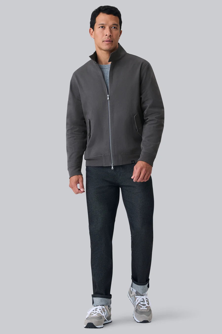 Close-up of a person wearing the MACK WELDON Twill Harrington Jacket in Shroom, featuring a zip front and buttoned flap pocket. Their arm is relaxed by their side and dark denim jeans are partially visible.