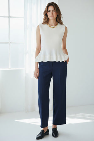 A person wears the MEIMEIJ - PLEATED SLEEVELESS TOP by MEIMEIJ with a silver chain necklace and a vibrant floral skirt, set against a plain white background—a chic choice to pair with summer trousers for effortless style.