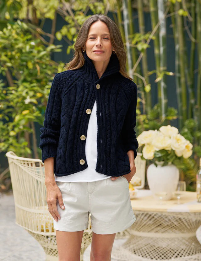 A FRANK &amp; EILEEN Mini Cotswolds Cropped Cable Knit Cardigan in Marine is laid flat on a white background, featuring long sleeves, a high collar, and four large tan buttons. The inner label reads &quot;Frank &amp; Eileen.
