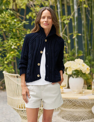 A FRANK & EILEEN Mini Cotswolds Cropped Cable Knit Cardigan in Marine is laid flat on a white background, featuring long sleeves, a high collar, and four large tan buttons. The inner label reads "Frank & Eileen.