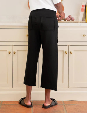 The FRANK & EILEEN Penny Patch Pocket Sweatpant in black features a cropped wide-leg style, elastic drawstring waistband, and large front patch pockets, crafted from cozy triple fleece and shown flat on a white background.