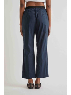 Someone wearing MEIMEIJ Pull On Cotton Pant in Black, a white top, and black open-toe sandals stands against a plain light background.