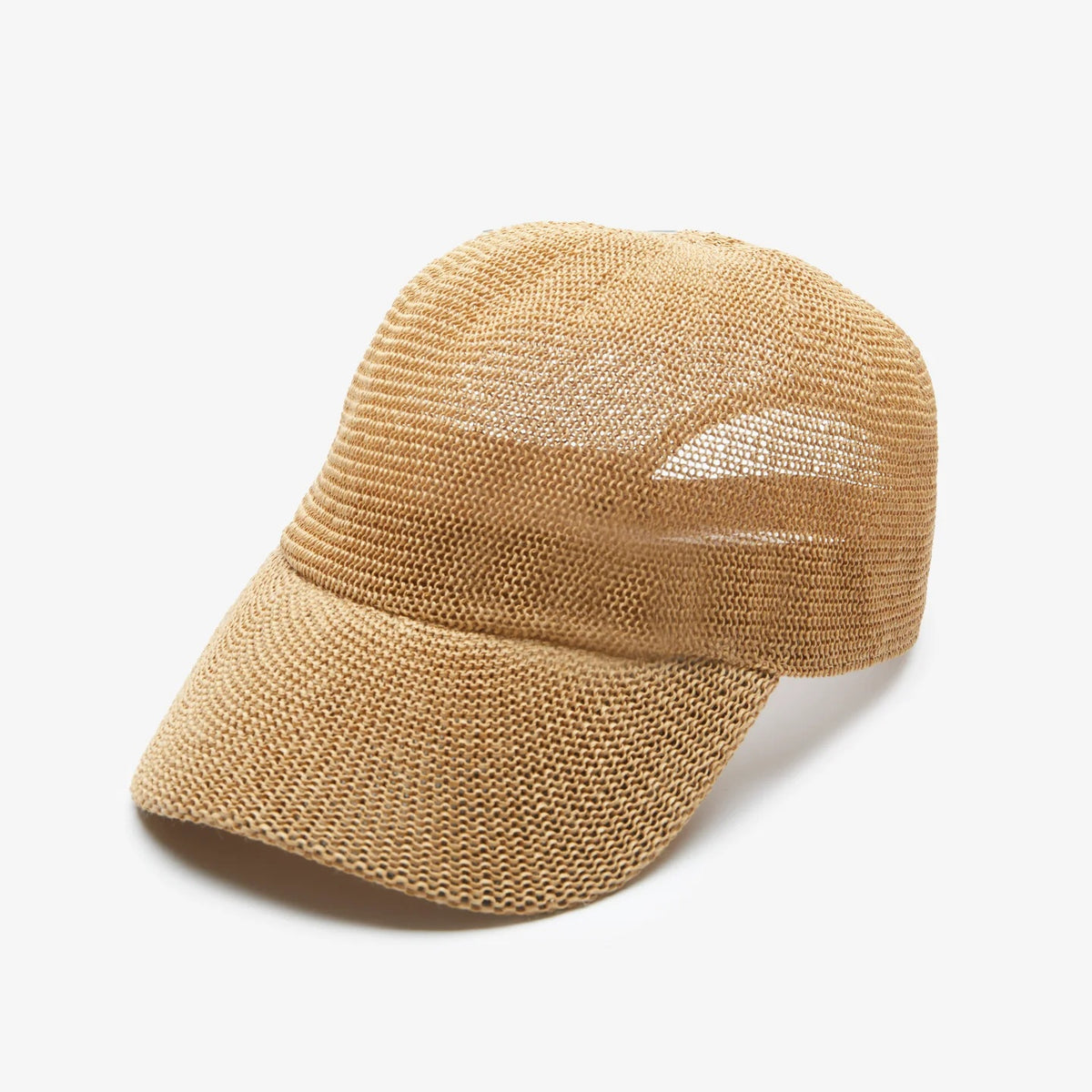A woman with long wavy blonde hair wears the WYETH HATS - PAULA MESH CAP IN CAMEL by WYETH, featuring UPF 50+ protection, and a white tank top, seated against a plain light-colored background.