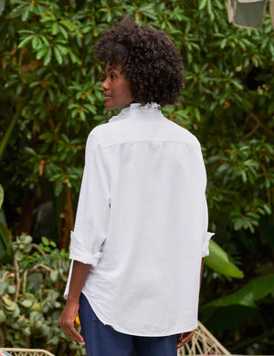 The FRANK & EILEEN Ruffle Eileen Ruffle Collar Button Up Shirt in White Famous Denim features rolled-up long sleeves, a ruffled collar, and a single chest pocket, shown against a white background.
