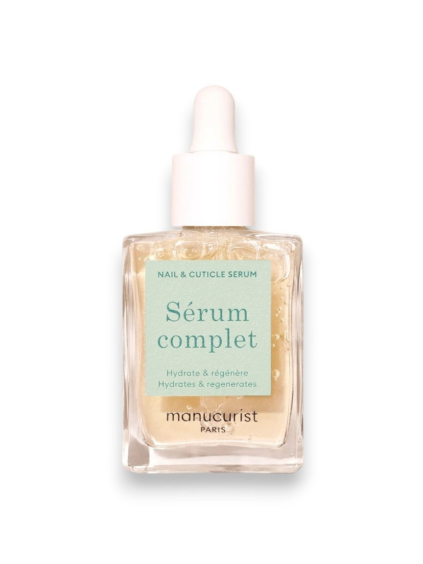 A glass dropper dispenses clear MANICURIST - SERUM COMPLET NAIL HYDRATING SERUM by MANUCURIST INC into a square bottle with a white dropper cap and mint green label, designed to hydrate and restore nails and cuticles.