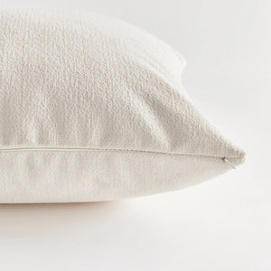 Against a plain white background, the NAPA HOME AND GARDEN - COOPER SQUARE INDOOR-OUTDOOR PILLOW 20", with its soft and fluffy Jacquard texture, appears smooth and slightly plump, ideal for resting or sleeping in any weather-resistant setting.