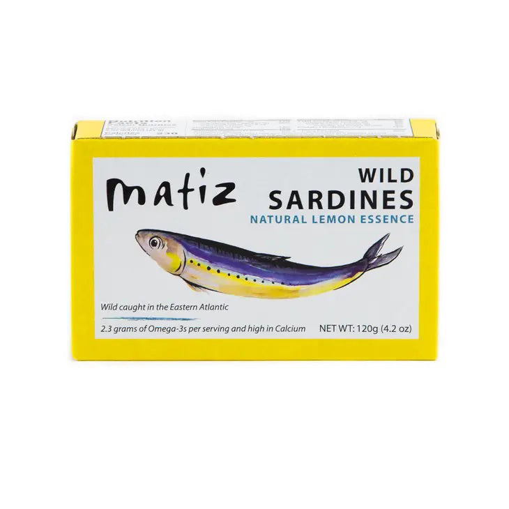 MATIZ ESPANA's MATIZ - SARDINES WITH LEMON comes in a yellow box featuring a sardine illustration. Key highlights include "Wild caught in the Eastern Atlantic," "2.3 grams of Omega-3s," "High in Calcium," and "Rich flavor." Contains 120g (4.2 oz); includes Spanish olive oil and lemon essence.