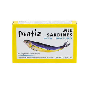 MATIZ ESPANA's MATIZ - SARDINES WITH LEMON comes in a yellow box featuring a sardine illustration. Key highlights include "Wild caught in the Eastern Atlantic," "2.3 grams of Omega-3s," "High in Calcium," and "Rich flavor." Contains 120g (4.2 oz); includes Spanish olive oil and lemon essence.