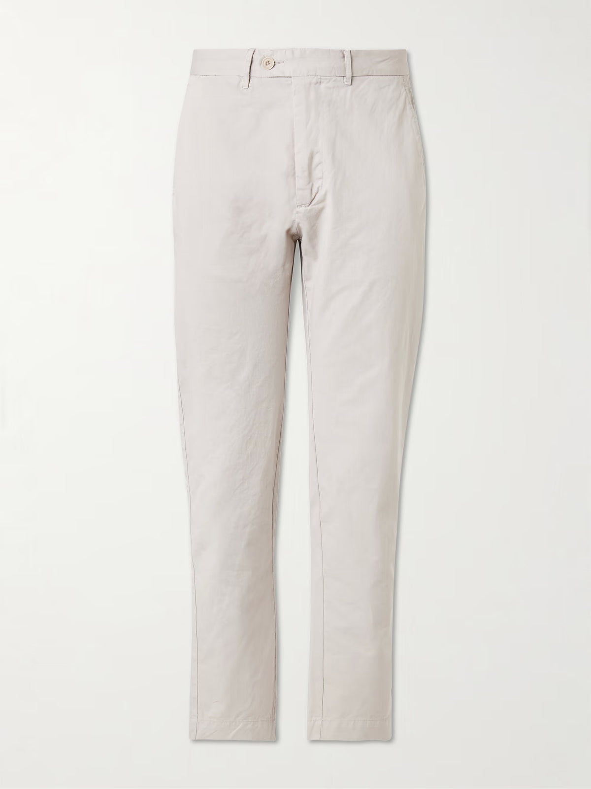 A person wearing HARTFORD - TAYLOR PANTS IN STONE, a white long-sleeve shirt, and black loafers stands on a wooden floor against a neutral wall.