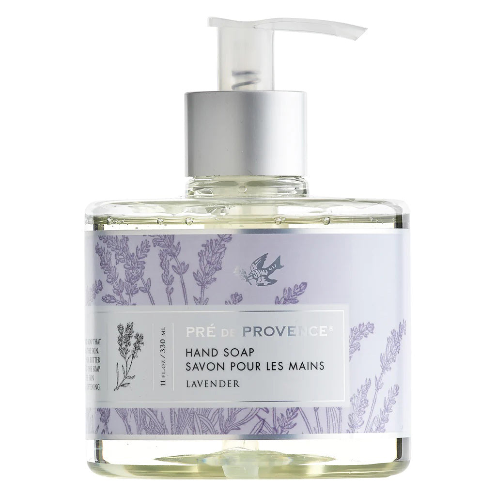 A clear pump bottle labeled "EUROPEAN SOAPS, LLC" contains lavender-scented HERITAGE LIQUID SOAP enriched with glycerin. The label features lavender plant illustrations and text in both English and French. The light purple liquid soap inside adds to the packaging's elegant and minimalistic appeal.