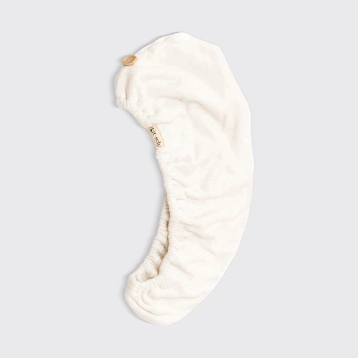 The KITSCH - QUICK DRY HAIR TOWEL, made from organic cotton and bamboo, features eco-friendly packaging with a teardrop design that promises frizz reduction for fine, curly, or straight hair. It includes an image of a person wearing the towel.
