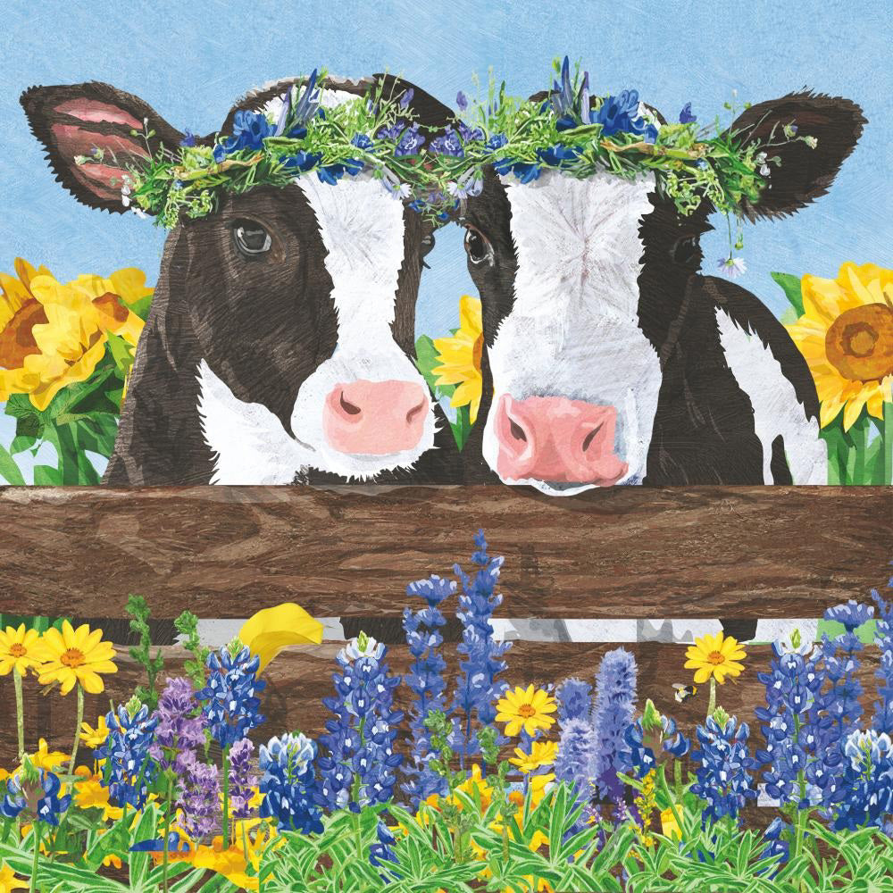 The BORDEN AND CLOVER BEVERAGE NAPKINS by PAPER PRODUCTS DESIGN feature two cows with flower crowns standing behind a wooden fence, surrounded by sunflowers and bluebonnets under a light blue sky, depicted on the softest 3-ply paper.
