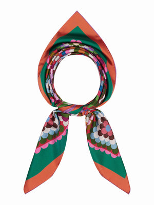 A vibrant quilt showcases geometric squares in pink, red, green, brown, white, and black with green and red borders—each echoing the bold design of the FRANCO FERRARI - CIALDA REVERSIBLE SILK SCARF by FRANCO FERRARI.