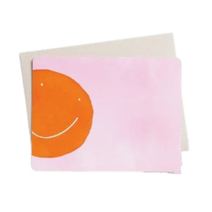 E. FRANCES PAPER’s "Flat Notes Orange Smiley" set features a simple orange smiley face on pink, paired with a plain white envelope—ideal for sending illustrated notecards or thoughtful, handwritten notes.