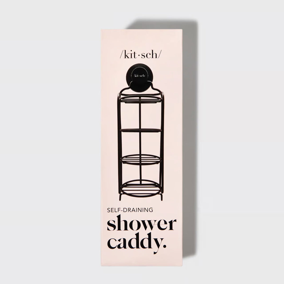The image depicts a black, rust-proof SELF DRAINING SHOWER CADDY by KITSCH holding four round shampoo bars in various colors: pink, green, white, and grey. Next to the eco-friendly caddy is a tall box featuring an illustration of the caddy and labeled with "/kit·sch/ SELF DRAINING SHOWER CADDY.