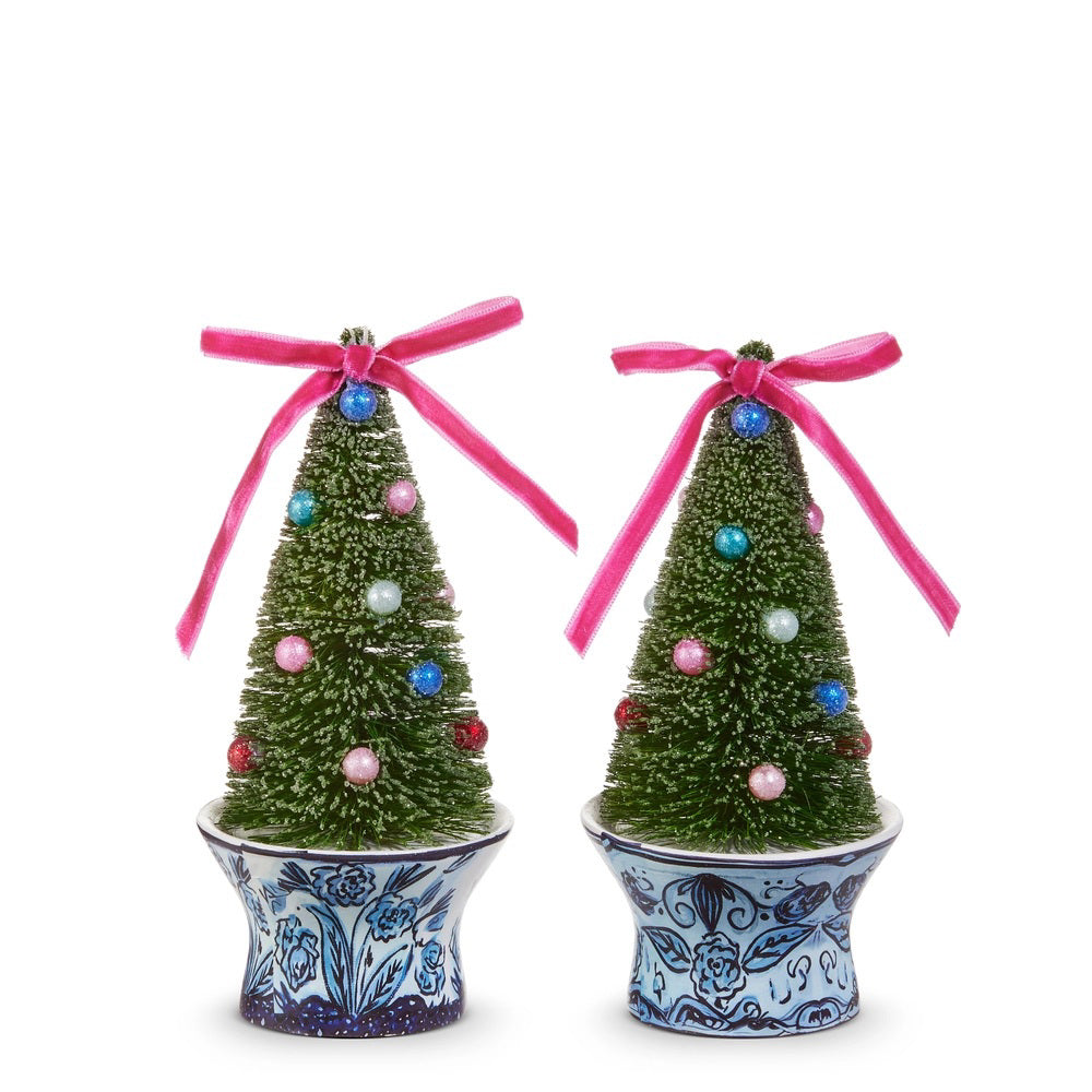 Two NOTTLE BRUSH TREE IN CHINOISERIE POT ORNAMENTS by RAZ IMPORTS—small artificial sisal Christmas trees with colorful ornaments and pink bows, each in a blue and white floral ceramic pot, displayed on a white background.