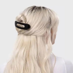 Two sustainable rectangular hair clips, one solid black and the other with a brown and black tortoiseshell pattern, rest on a light pink card. The card emphasizes the recycled materials of "KITSCH - FLAT LAY CLAW CLIP 2 PC," showcasing their style and eco-friendly commitment.