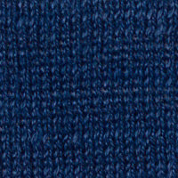 A person with long dark hair is wearing a KINROSS CASHMERE OPENWORK VEE NECK SWEATER by KINROSS, featuring a light gray knit made of 100% linen and a chevron pattern. They have paired it with white pants, standing against a plain white background with one hand resting on their hip.