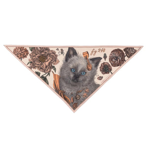 A person in a cream-colored shirt and skirt is seen from the back, wearing a SABINA SAVAGE - RING A RING O' ROSES silk twill triangle scarf by SABINA SAVAGE ENGLAND, featuring a fluffy Ragdoll kitten with blue eyes, framed by English garden flowers.