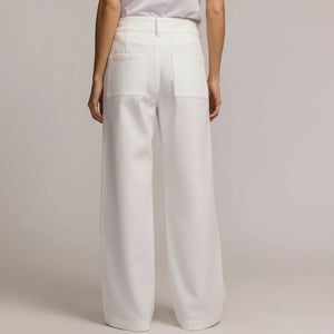 A person models the HINSON WU KELLY TRAVELERS TWILL PANT IN WHITE, featuring high-waisted, wide-leg stretch twill with large front pockets and double button closure—ideal travel-friendly style from HINSON WU.