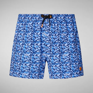 SAVE THE DUCK - ADEMIR SWIM TRUNKS IN BLUE SHARK: Quick-dry recycled polyester men's swim trunks featuring a blue and navy shark print, drawstring waistband, orange logo patch on the lower left leg, and plain light gray background.