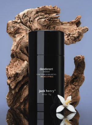 A person holds a black stick of JACK HENRY - DEODORANT HINOKI CYPRESS near their lips. Text highlights zinc ricinoleate, lactobacillus ferment, magnesium, and meadowfoam seed in this natural, aluminum-free JACK HENRY formula.
