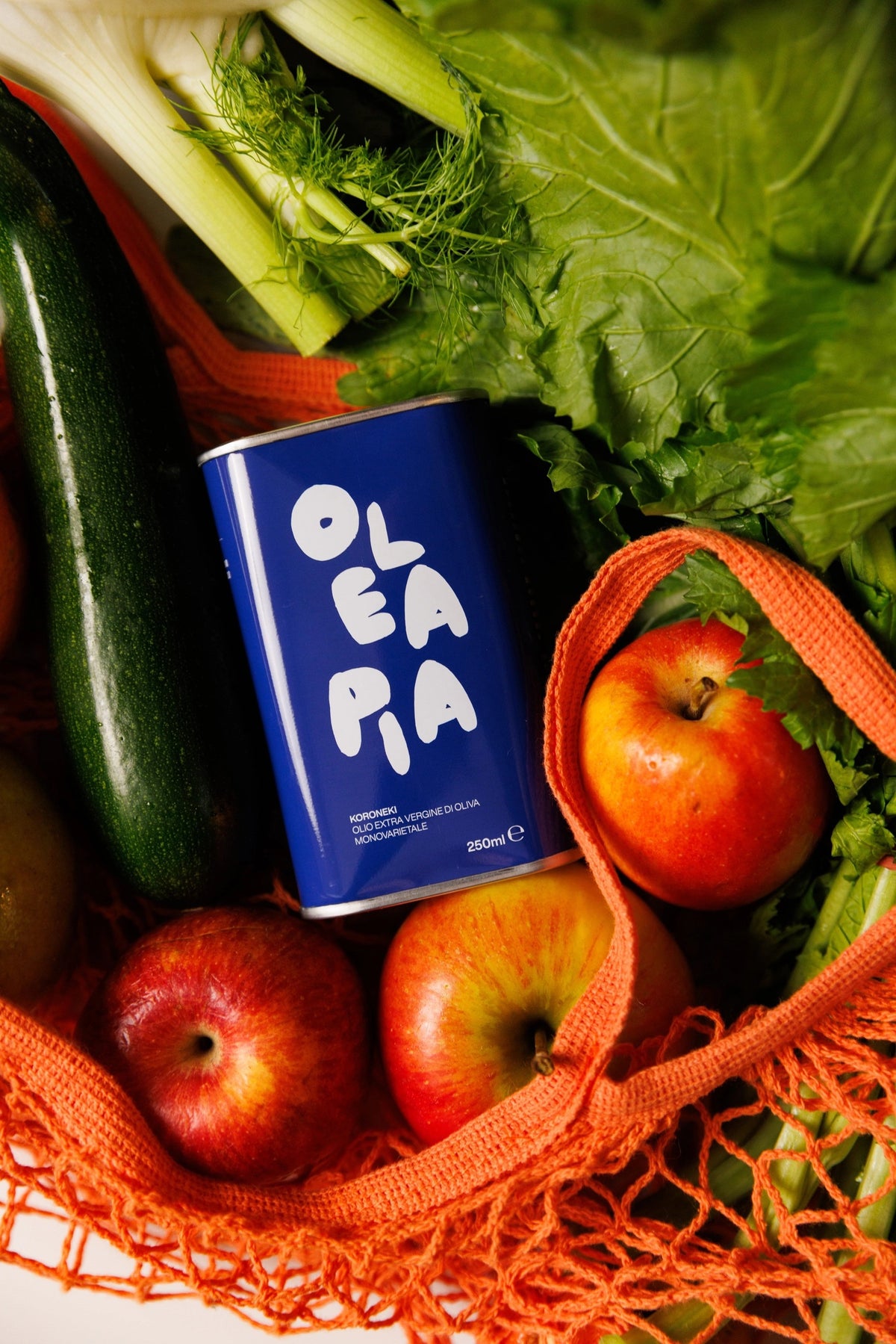 A 250ml blue tin labeled “OLEA PIA” in bold white letters contains OLEA PIA - MONOVARIETAL KORONEIKI EXTRA VIRGIN OLIVE OIL, a premium Greek olive oil that is cold-pressed to retain its exceptional flavor and aroma.