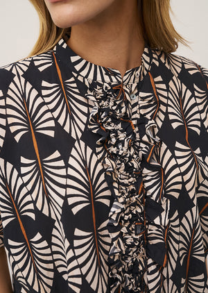 A woman with long blonde hair models the 0039 ITALY DAISY DRESS IN BLACK PRINT, a short-sleeved dress featuring a bold black and white leaf pattern with ruffled details and a flattering O-shape silhouette against a plain light background.