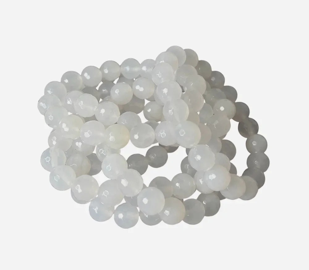 The ANN LIGHTFOOT - 10MM Faceted White Moonstone Bracelet features polished, semi-translucent round beads and is displayed on a plain white background.
