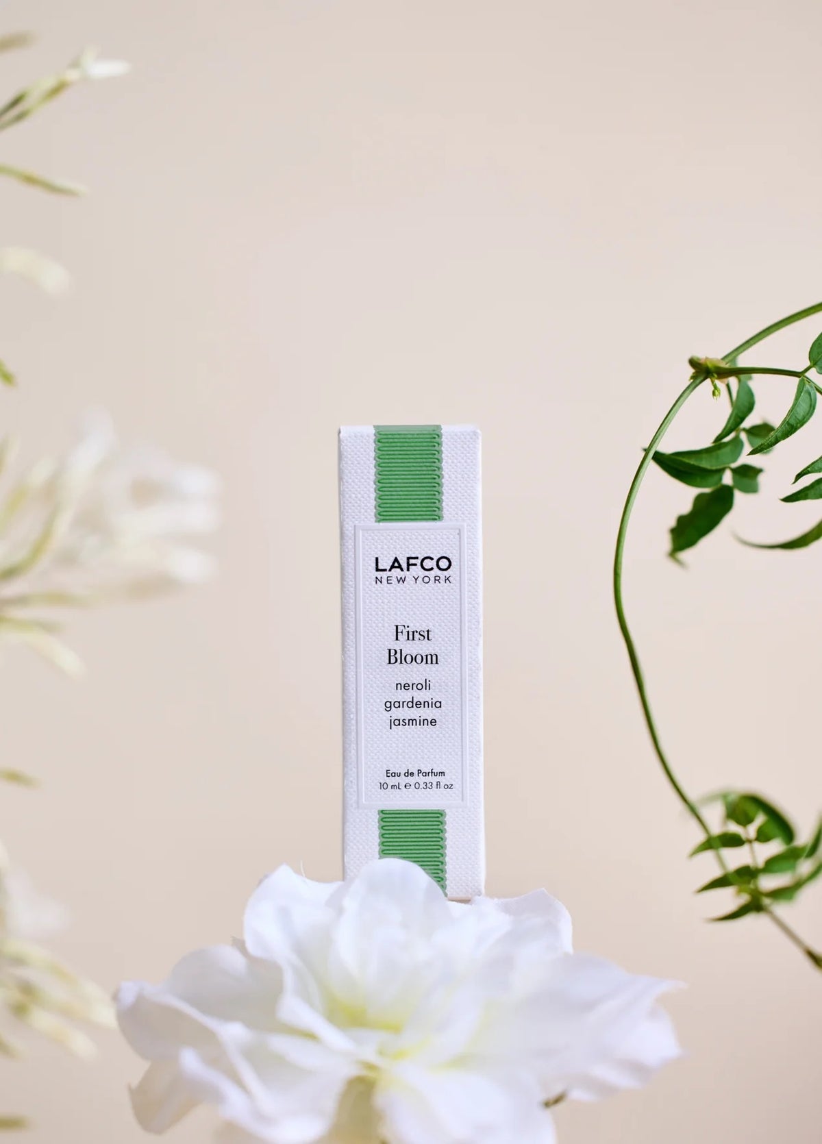 A 10ml bottle of LAFCO Fine Fragrance, First Bloom, a vegan eau de parfum that captures the freshness of spring with luminous neroli and radiant floral notes. Presented by LAFCO, this scent features a marbled green and white cap atop vibrant yellow liquid.