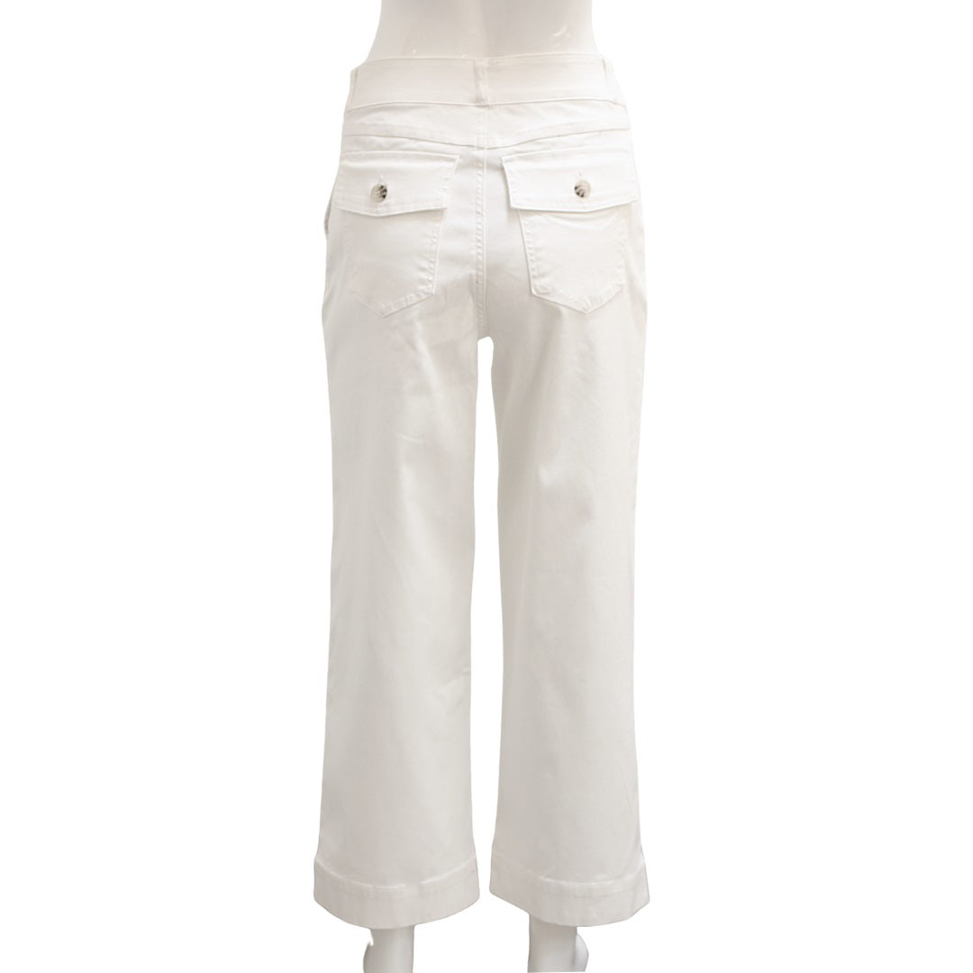 A woman stands confidently with her arms crossed, modeling a long-sleeve white top paired with high-waisted, wide-leg brown SPANX - STRETCH TWILL CROPPED PANTS. She completes the look with white slip-on shoes and is posed against a plain white background, gazing directly at the camera.