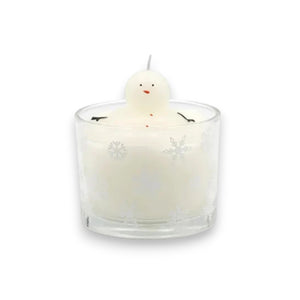 The CREATIVE COOP MELTING SNOWMAN CANDLE is a white holiday candle in a glass holder with snowflakes and a small snowman figure on top, set against a light, textured backdrop—perfect for festive winter decor.