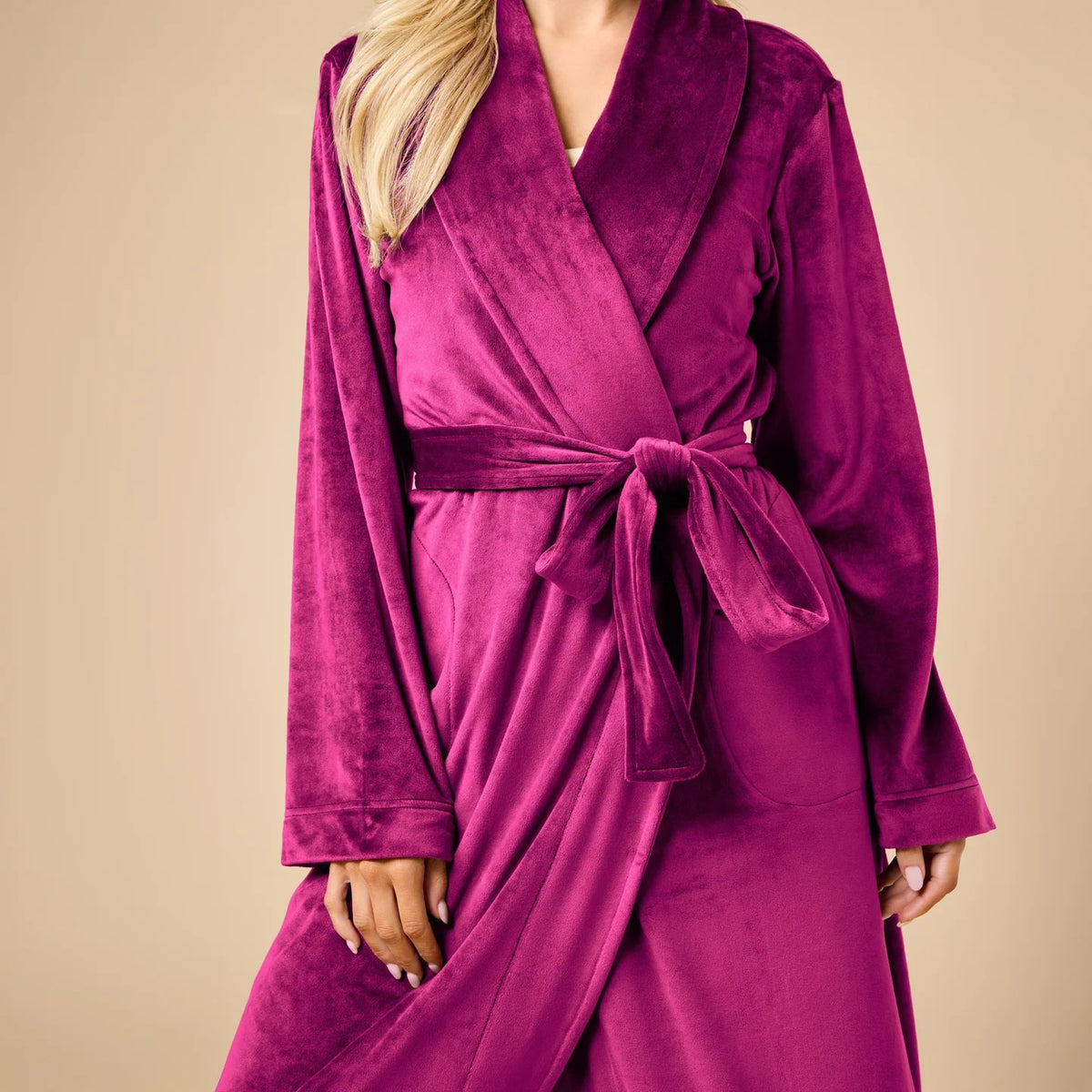 A person wearing a beige SOFTIES - SERENITY WRAP ROBE featuring a wrap silhouette with a tie waist and side pockets.