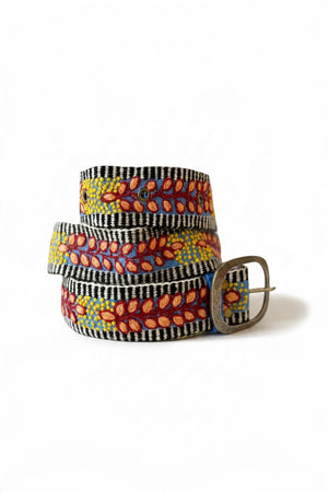 The JENNY KRAUSS - GROWING SEASON BELT by JENNY KRAUSS is a coiled, handcrafted Peruvian belt with black and white stripes, red and yellow leaf and dot embroidery, silver metal buckle, shown on a white surface.