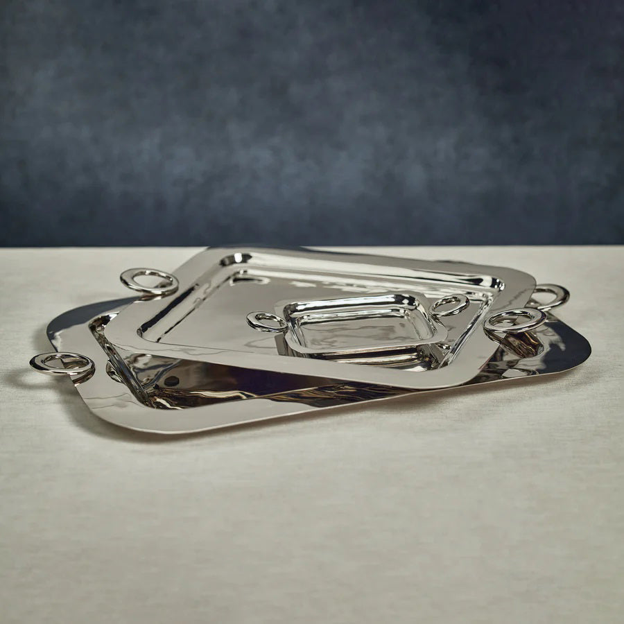 The ZODAX POLISHED BRASS SERVING TRAY is a rectangular metal tray with rounded corners and two circular handles, shown on a white background. Size: 21.25 in x 15.5 in x 1 in.