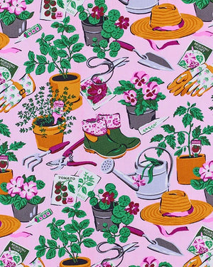 A woman with long blonde hair stands against a plain white wall, looking slightly to the side and smiling softly, wearing the PRINTFRESH - GREEN THUMB BACK TO BED PAJAMA SHORT SET by PRINTFRESH—a colorful floral sleepwear set inspired by vintage styles.