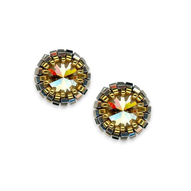 The MIGUEL ASES - SWAROVSKI MIYUKI POST EARRINGS, handcrafted by MIGUEL ASES, INC., showcase a stunning round design. Each earring features a central faceted golden-yellow gemstone encircled by concentric rings of small metallic and pyrite beads that reflect light in shimmering silver and gold hues, creating a beautiful sunburst pattern.