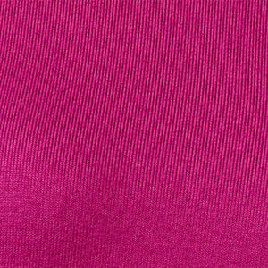 A woman wears a SOFTIES - DREAM RELAXED V-NECK WITH CAPRI LOUNGE SET in magenta, featuring a V-neck top with elbow-length sleeves and matching cropped drawstring pants, paired with cream-colored loafers.