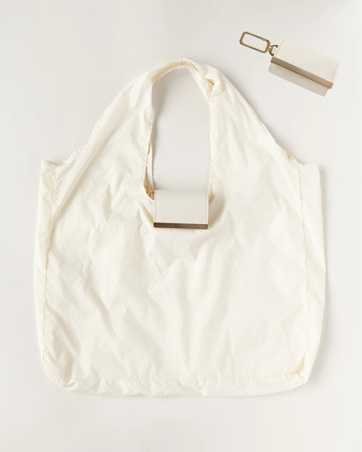 The KEOTE - KEYCHAIN TOTE IN CREAM by KEOTE is a stylish white reusable tote with a rectangular case attached to the handle and a matching cream keychain tote case with keyring, displayed on a white background.