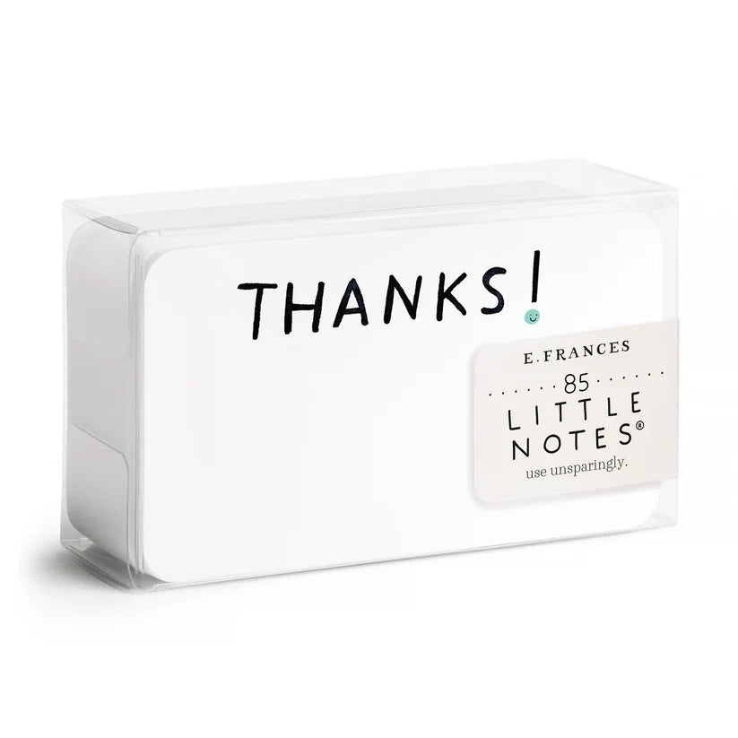A clear plastic box contains E. Frances Paper - Thanks Little Notes, each decorated with "THANKS!" on the cover. These charming cards showcase a subtle watercolor design, encouraging generous use for any occasion.