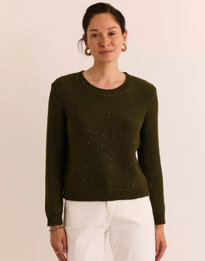 A person wearing the HINSON WU Queenie Long Sleeve Sequin Sweater in Oregano—an everyday essential crafted from breathable cotton with subtle sequin embellishments—paired with gold hoop earrings and touching their collar with one hand.