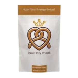 A white pouch labeled "QUEEN CITY CRUNCH - CINNAMON SUGAR" features a crowned pretzel and the phrase "Knot Your Average Pretzel" at the top, hinting at craveable sweet-and-salty cinnamon sugar snacks.