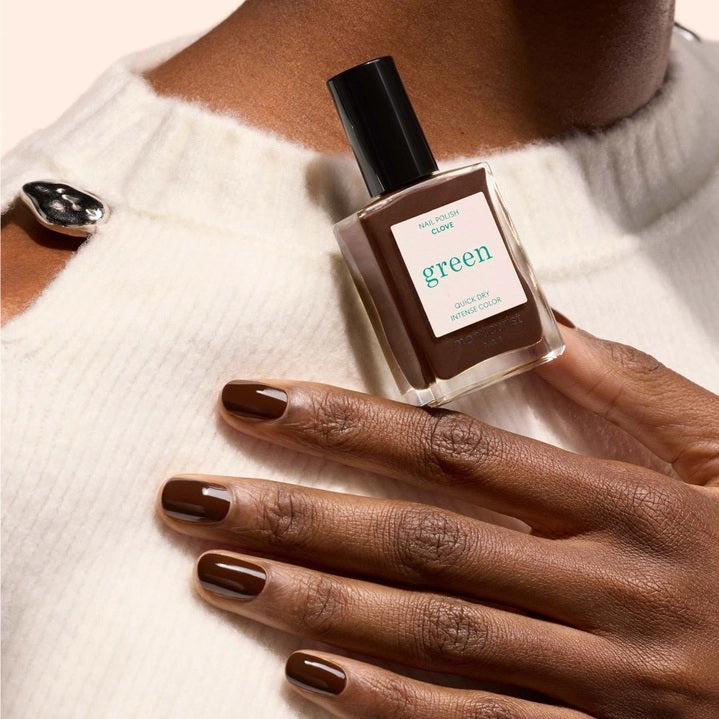 A bottle of MANUCURIST - GREEN™ Nail Polish in Clove by MANUCURIST INC, featuring a rich chocolate brown shade and a black cap. The label reads “green quick dry intense color.”.