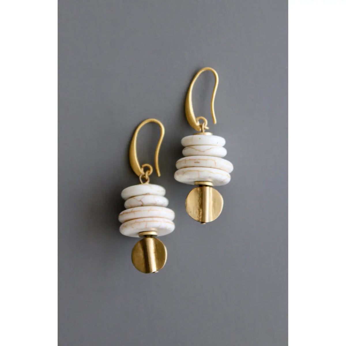 DAVID AUBREY - WHITE MAGNESITE AND BRASS EARRINGS feature stacked white magnesite beads, brass accents, and gold hooks. Handcrafted jewelry by DAVID AUBREY, New Jersey, shown on a gray background.