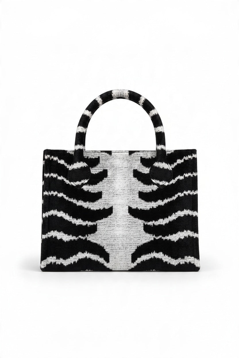 BALDIZ - ORIGINAL ZEBRA AVERY BAG, a structured zebra-print tote featuring two top handles, a center zipper, and protective purse feet.