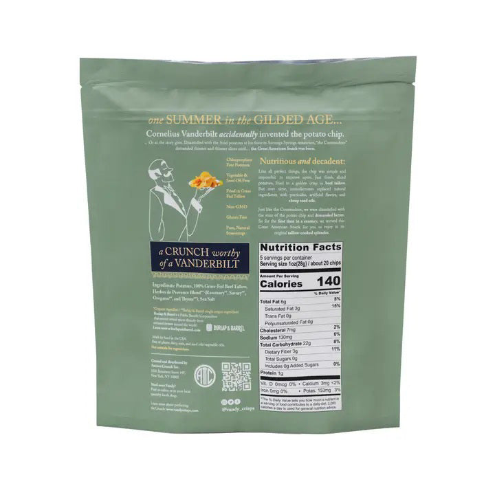 An upright green bag of ANCIENT CRUNCH - VANDY POTATO CHIPS, HERBES DE PROVENCE features gold accents and a gate design, with tallow-cooked potato chips scattered at its base.