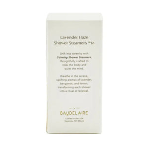 A BAUDELAIRE - CALM LAVENDER HAZE SHOWER STEAMER rests atop a slatted bamboo soap dish emblazoned with “BAUDELAIRE,” water droplets scattered on the white surface below—creating a tranquil scene evocative of soothing aromatherapy.