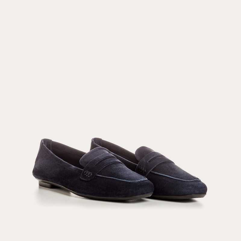 Six pairs of REQINS HEMA suede loafers in marine, featuring a classic penny loafer design and timeless silhouette, are displayed on a light tan surface in various blue and green shades.