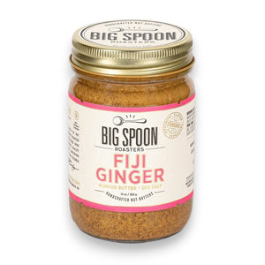 A jar of BIG SPOON ROASTERS - FIJI GINGER ALMOND, featuring a gold lid and a white label with pink accents that displays the brand name, flavor, and additional product information. The crystallized ginger-infused almond butter is visible through the clear jar.